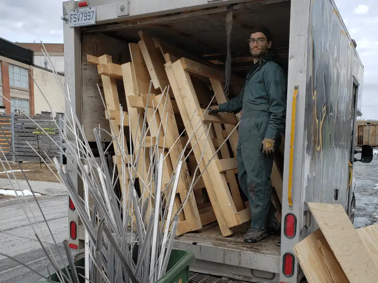 Travailleur Recyborg debout dans un camion contenant des palettes en bois
